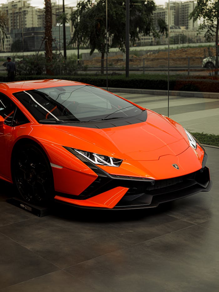 Vibrant orange sports car displayed elegantly in an urban showroom setting.