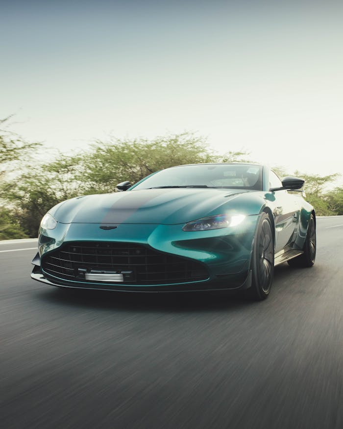 Aston Martin sports car speeding on a road in New Delhi, India during daytime.
