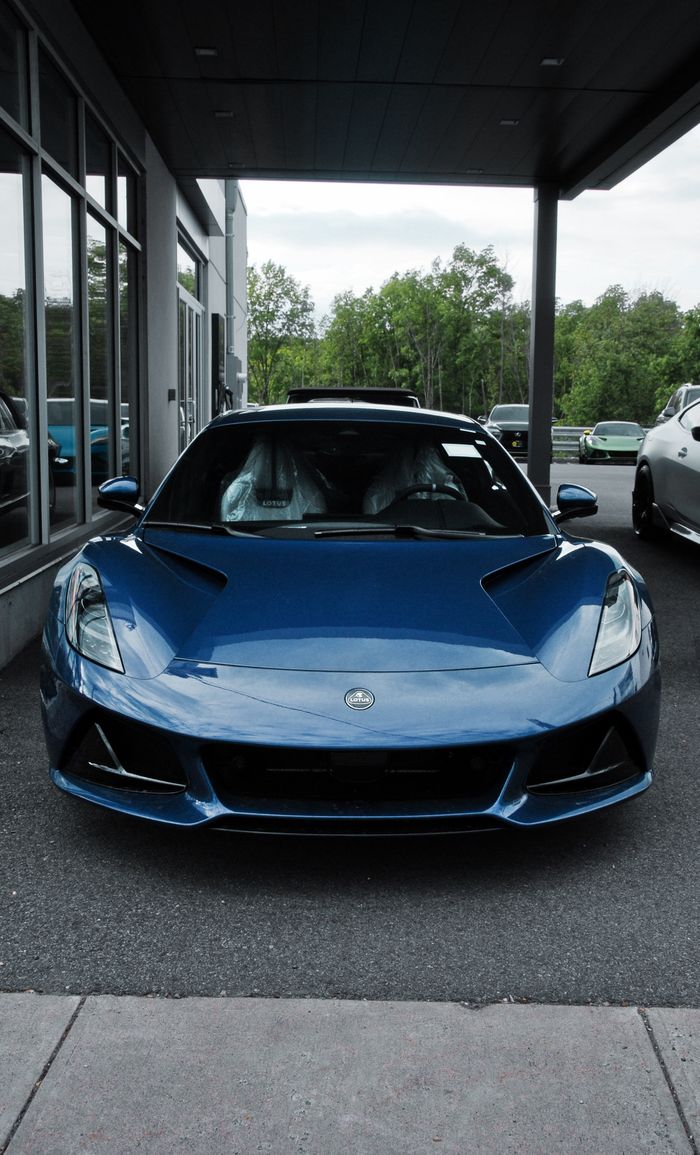 Front view of a blue sports car parked in an outdoor showroom with a modern backdrop.