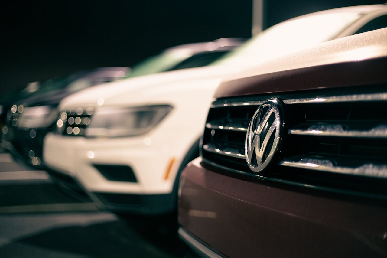 Front bumpers of expensive prestige automobiles at market retailing new cars at night